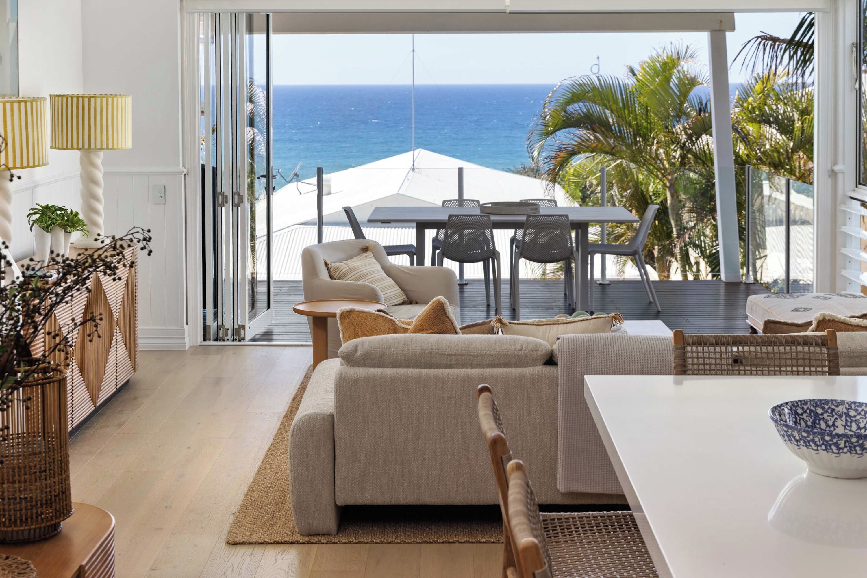 A modern living room with a view of the ocean, a dining area, and a large window.