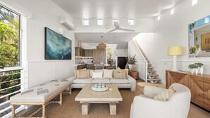 A modern living room with a sofa, coffee table, and a view of the kitchen. - Thalasa Two at Sunshine Beach (Sunshine Beach)