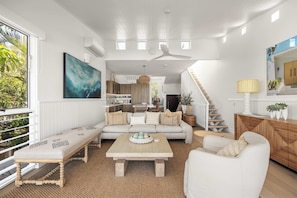 A modern living room with a sofa, coffee table, and a view of the kitchen. - Thalasa Two at Sunshine Beach (Sunshine Beach)