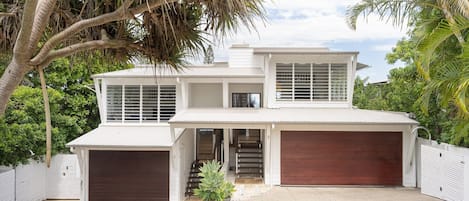Uma casa de dois andares com garagem, varanda coberta e escada que leva à entrada.