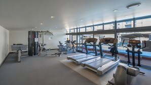 A modern gym with treadmills, elliptical machines, and weight equipment. - Mega Style Apartments Tribeca (East Melbourne)