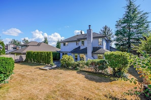 A residential house with a well-maintained lawn, a chimney, and a fenced yard.