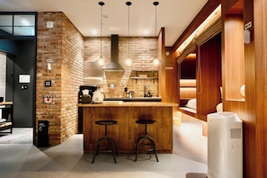 Une cuisine moderne avec un mur en briques, un bar en bois, deux tabourets et un purificateur d’air intégré.