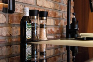 Un plan de travail de cuisine avec des bouteilles d’huile d’olive, des salières et des poivrières, et une machine à café.