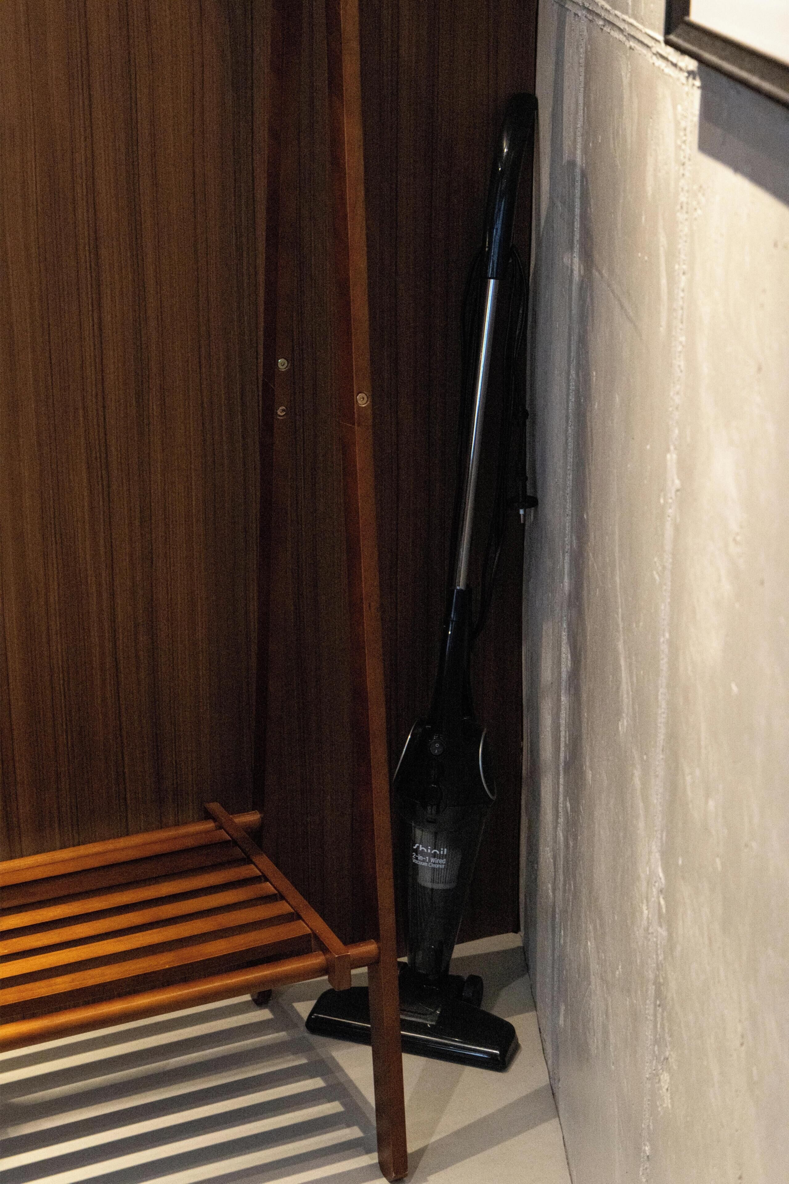 A wooden bench, a vacuum cleaner, and a white wall.