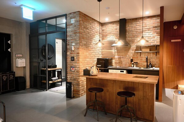Une cuisine moderne avec un mur en briques, un bar en bois et deux tabourets.