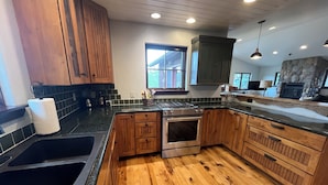 Cucina con pensili in legno, piano cottura in acciaio inossidabile, lavello e camino in pietra.