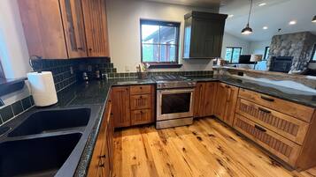 A kitchen with wooden cabinets, a stainless steel stove, a sink, and a stone fireplace.