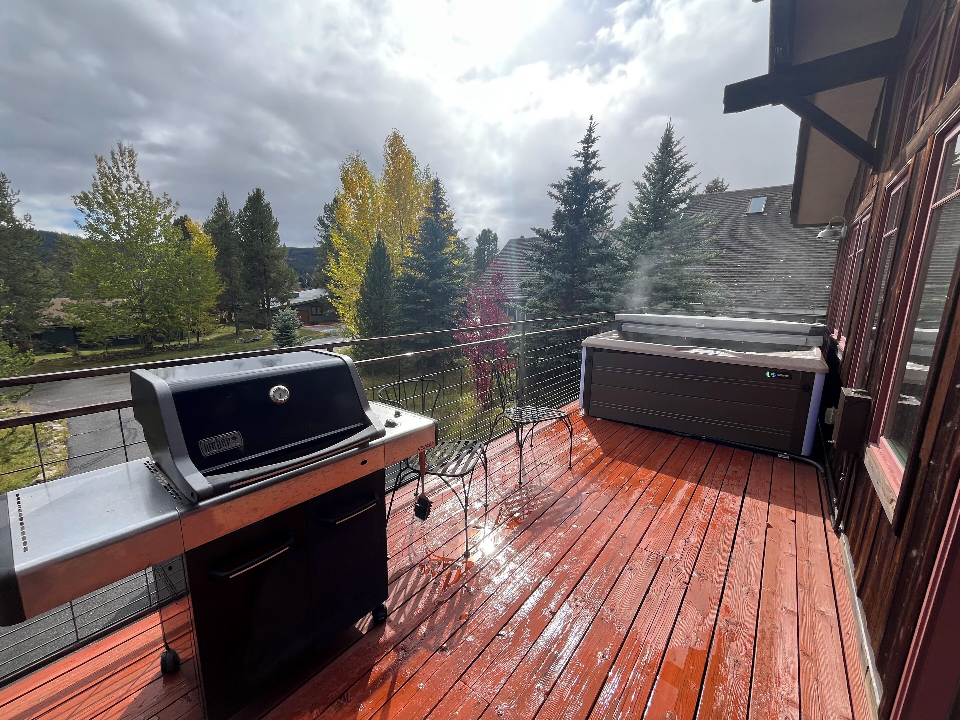 A wooden deck with a Weber grill and a hot tub.