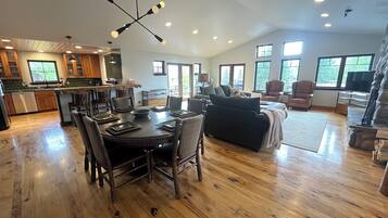 A spacious living area with a dining table, chairs, a sofa, and a TV.