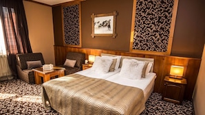 Une chambre d’hôtel avec un grand lit, deux tables de chevet, une chaise et une moquette à motifs.