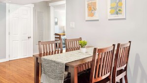 A dining area with a wooden table, four chairs, and a plant centerpiece. - Spacious 2BR Home, Backyard Parking & UW (Seattle)