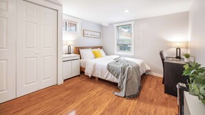 A bedroom with a bed, bedside table, lamp, and a window. - Spacious 2BR Home, Backyard Parking & UW (Seattle)