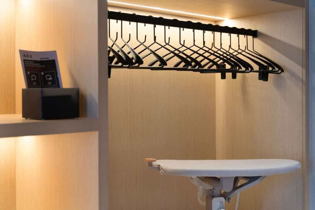 A room with a wall-mounted drying rack, a small shelf with a device, and a foldable table.