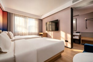 Una habitación de hotel con dos camas, televisión, escritorio y baño.