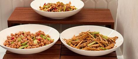 Three white bowls of food on wooden stands, a black tray with chopsticks, and a sign with Chinese characters.