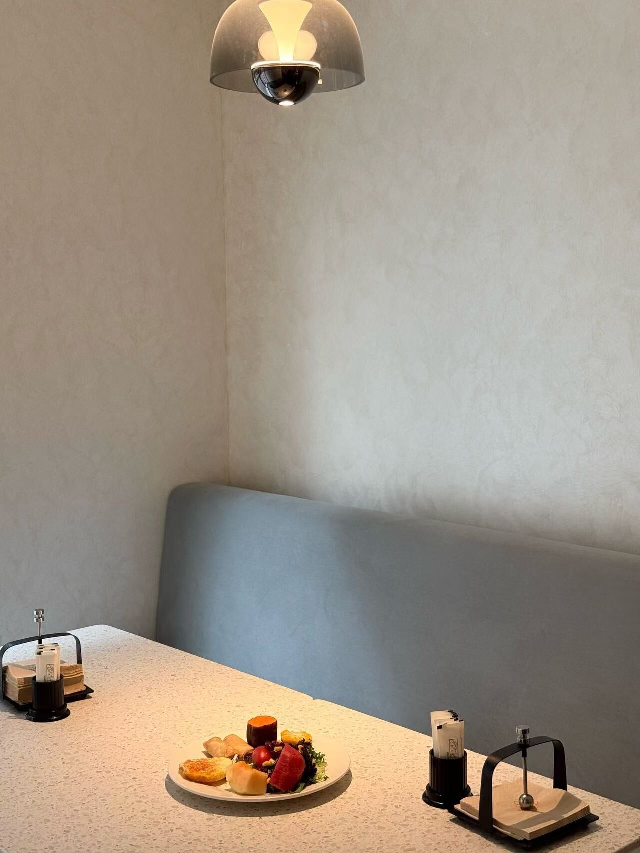 Een hoek van een kamer met een gedekte tafel, een bank en een lamp.