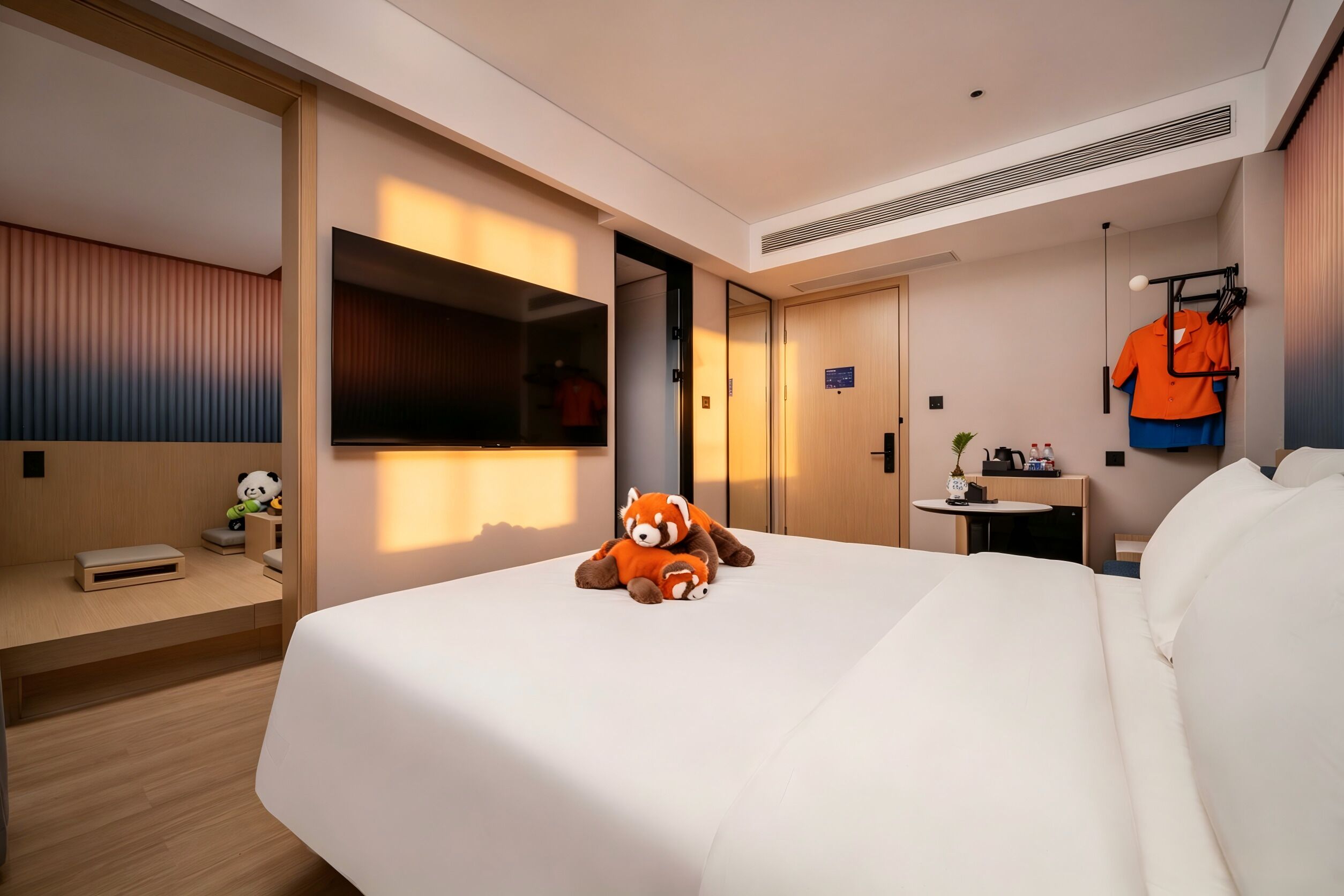 A hotel room with a bed, a desk, a TV, a wardrobe, and a coat rack.