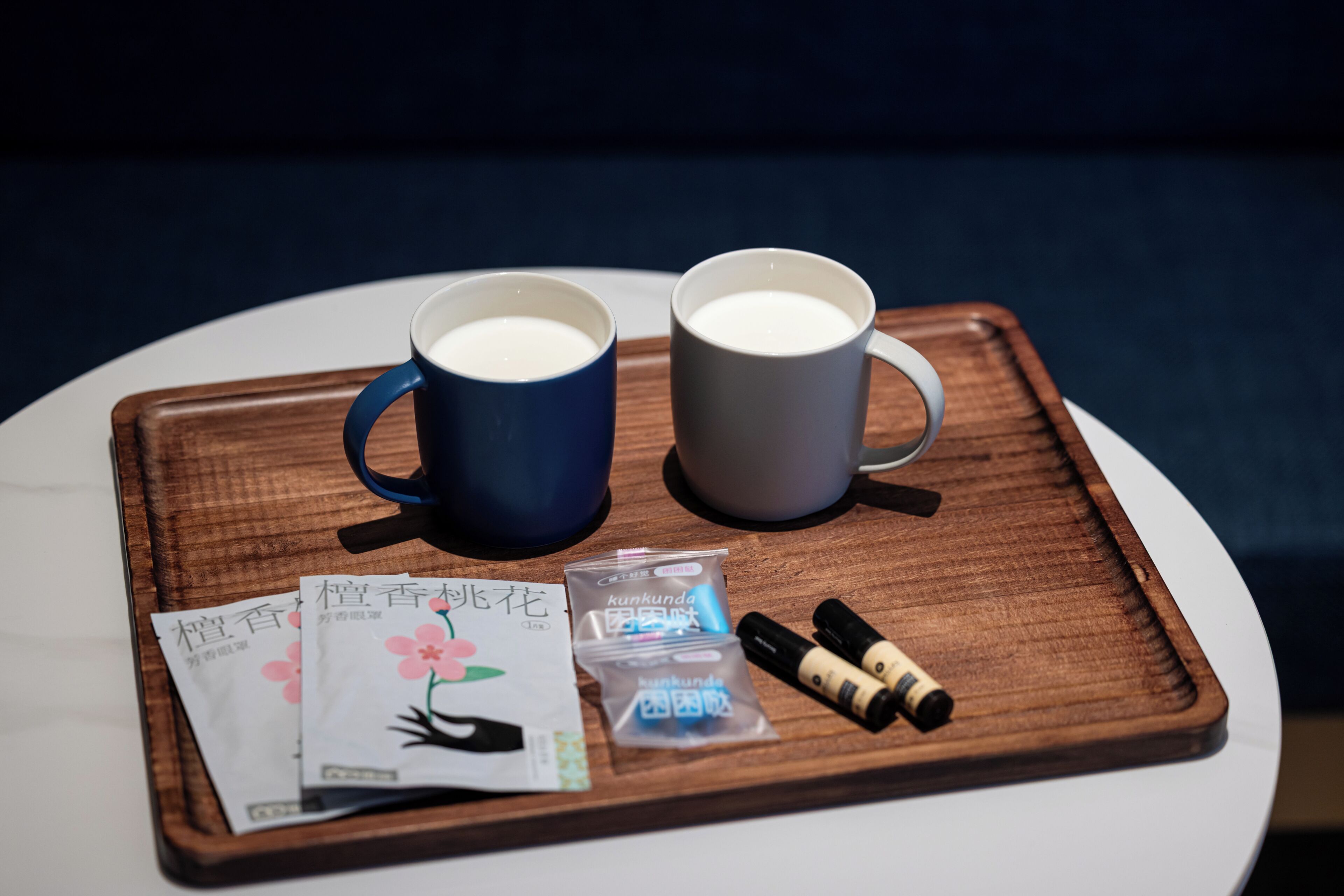 Un plateau avec deux tasses contenant une boisson, une carte et deux petits sachets, le tout posé sur une table ronde.