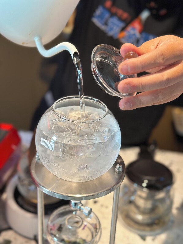 A person pouring water into a glass bowl on a stand. - CYBO Junting Shangpin Hotel (Chengdu Chunxi Road Tianfu Square Branch) (Chengdu)