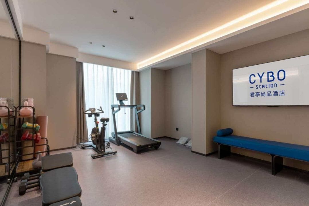 Zona de gimnasio con equipo de ejercicio, una cinta de correr y una banca.