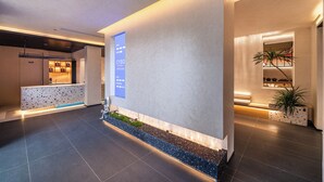 A modern lobby with a reception desk, a coffee bar, a plant, and a wall-mounted sign. - CYBO Junting Shangpin Hotel (Chengdu Chunxi Road Tianfu Square Branch) (Chengdu)