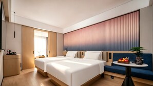 Ein modernes Hotelzimmer mit zwei Betten, einem Sofa, einem kleinen Tisch und einem Fernseher.