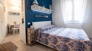 A bedroom with a bed, bedside tables, a dresser, a desk, and a chair. - Cosmopoli La Vela - Studio in Portoferraio (Portoferraio)