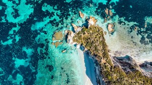 An aerial view of a coastal area with clear turquoise waters, rocky outcrops, and a narrow strip of land with sparse vegetation. - Cosmopoli La Vela - Studio in Portoferraio (Portoferraio)
