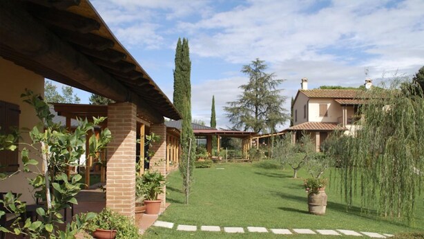 A villa with a covered patio, a well-maintained lawn, and a variety of plants. - Beautiful villa near Lake Trasimeno (Castiglione del Lago)
