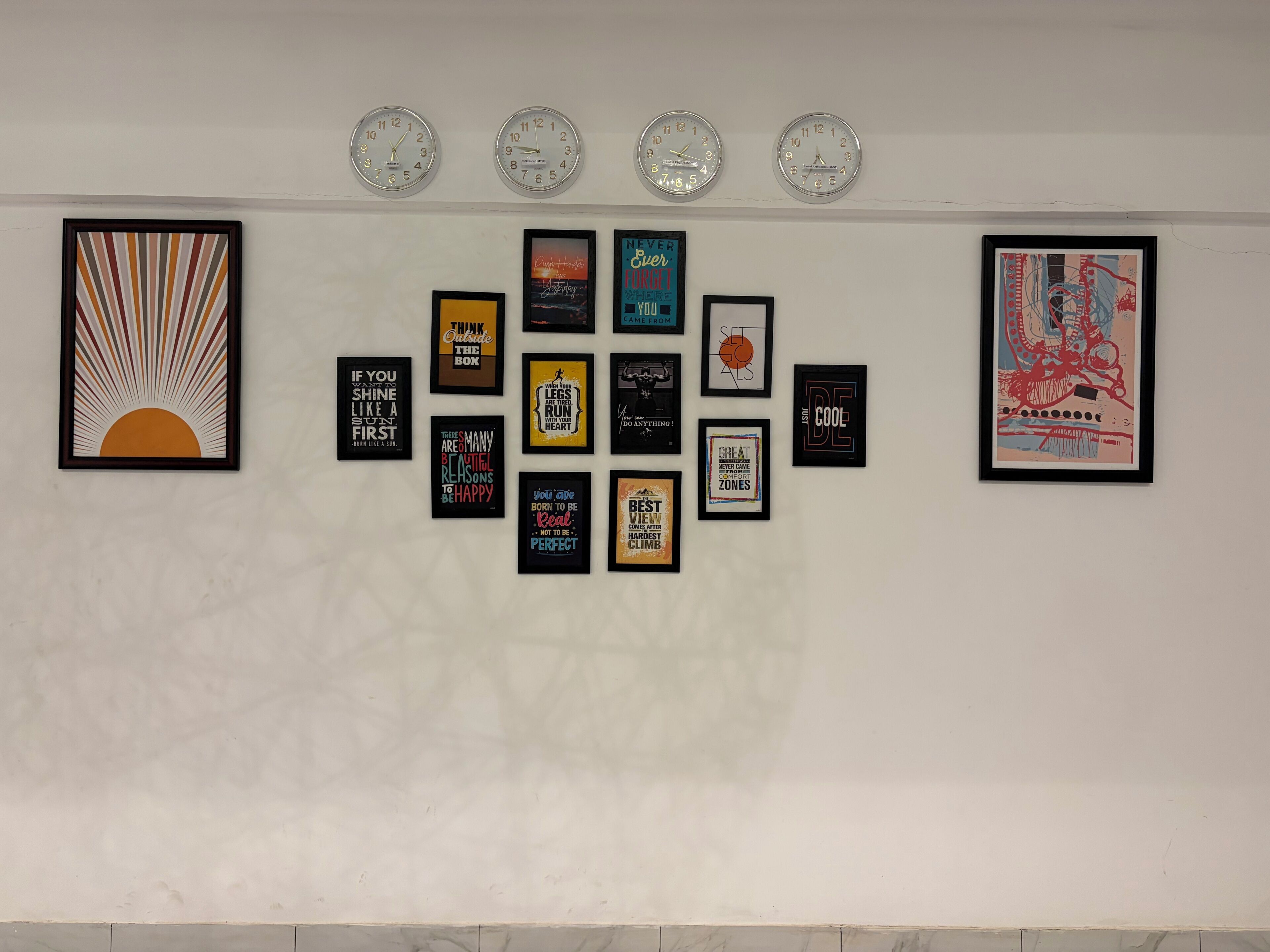 Una pared con cuatro relojes y varios carteles decorativos con frases motivadoras.