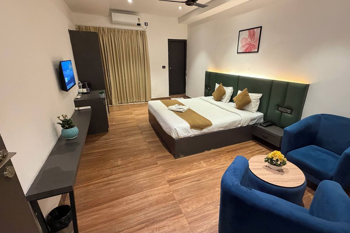 Ein modernes Hotelzimmer mit Bett, Schreibtisch, Stuhl und Fernseher.