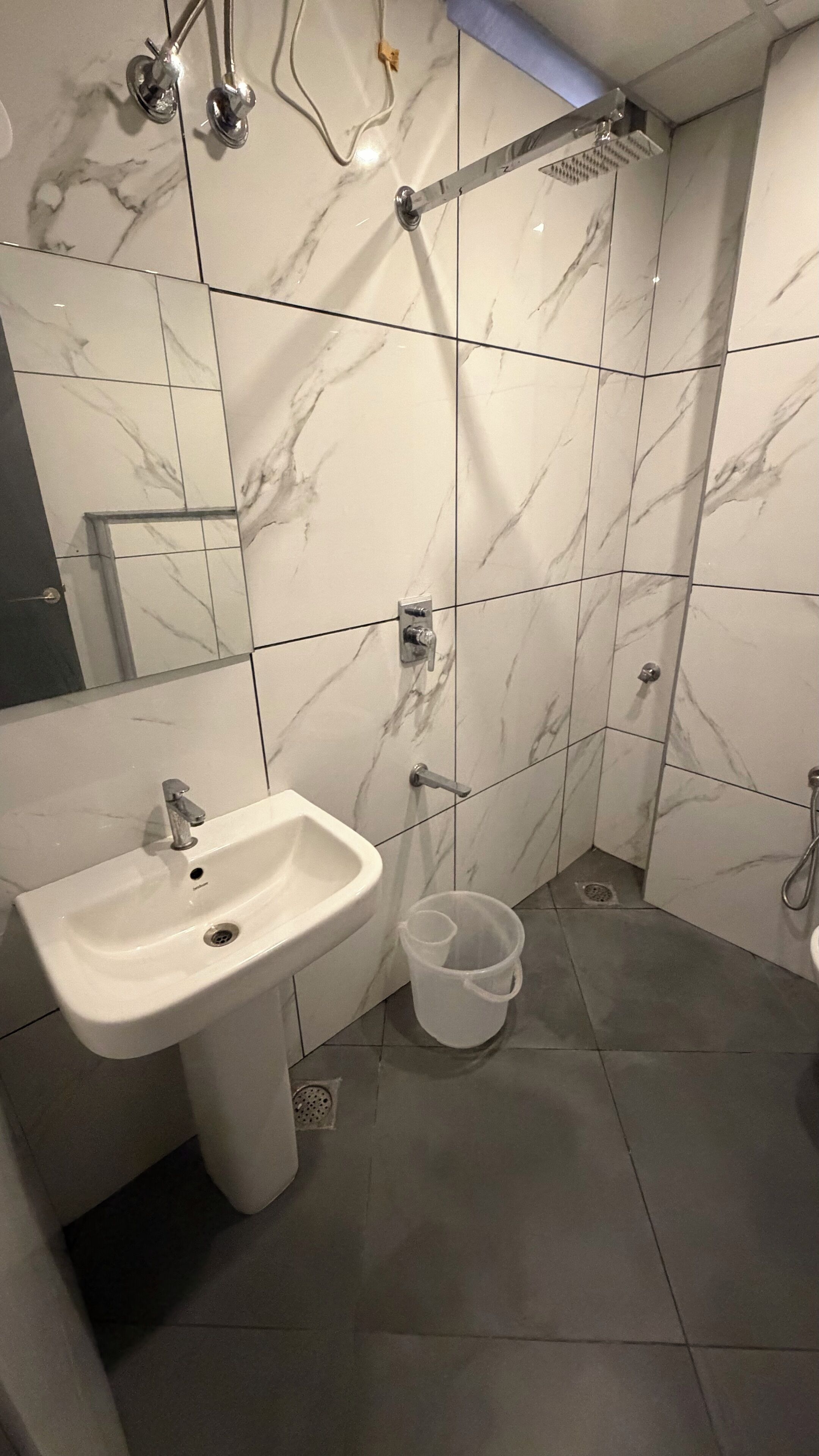 Un baño con lavamanos blanco, ducha e inodoro.