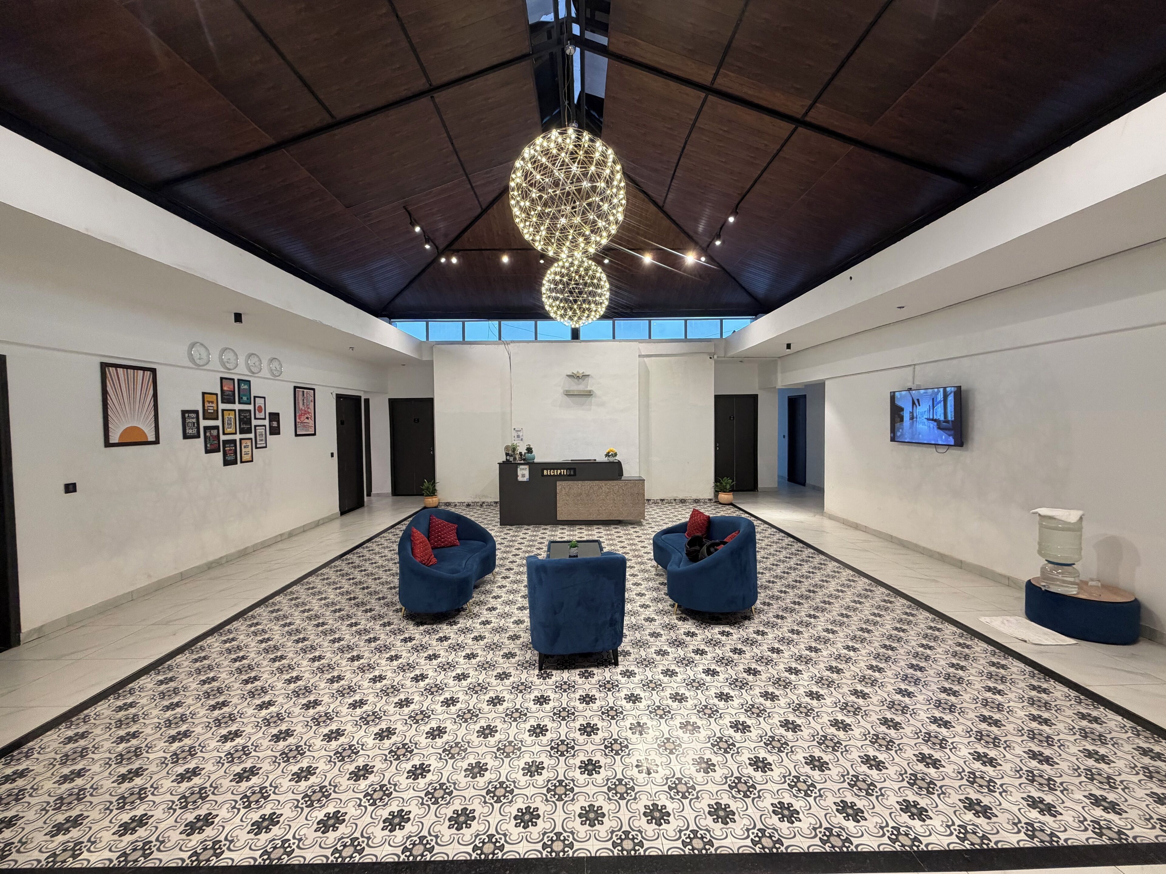 Un hall d’entrée spacieux au design moderne, comprenant un comptoir d’accueil, un espace salon et un grand lustre.
