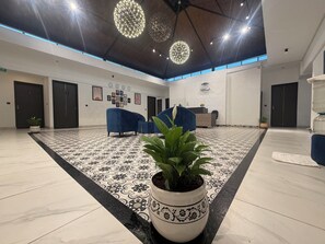 A lobby with a patterned floor, two reception desks, and a reception area with a plant. - Hotel Kingdom Suites (Bengaluru)