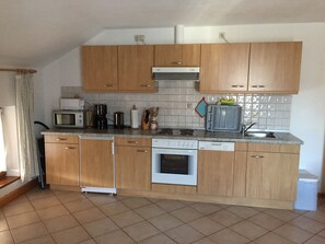 A compact kitchen with wooden cabinets, a microwave, a coffee maker, a dishwasher, and a stove. - Vacation apartment -6 persons, 75sqm, 3 bedrooms, balcony (Eggstätt)