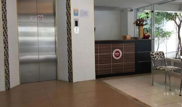 Una zona de recepción con un mostrador de madera, una silla y un cartel en la pared.