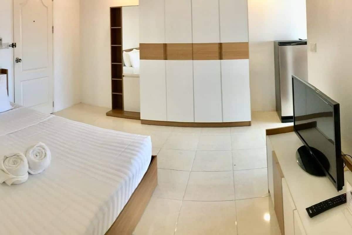 Une chambre d’hôtel moderne avec un grand lit, une télévision et une armoire.