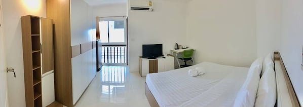 A hotel room with a bed, a TV, a desk with a chair, and a wardrobe. - Grandview Ladprao Hotel (Bangkok)