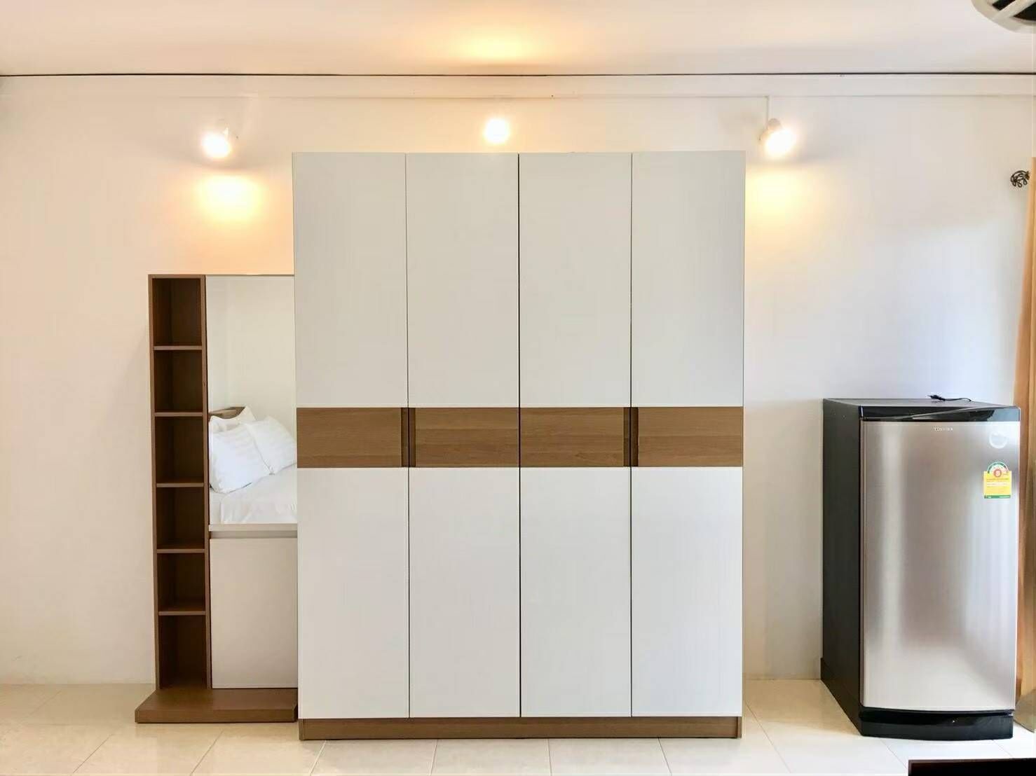 Een moderne kamer met een kledingkast, een ingebouwde plank en een koelkast.