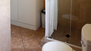 Et badeværelse med brusebad, toilet og et garderobeskab.