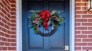 A dark blue door with a wreath and red bow, set in a brick wall.