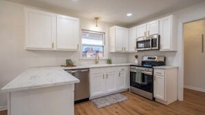 A modern kitchen with white cabinets, stainless steel appliances, and a marble countertop.