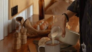 A person pouring milk into a mug on a wooden kitchen counter. - Sunsets, outdoor bath, mountain views, fire pit (Marotiri)
