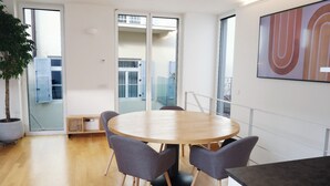 A modern conference room with a round table, four grey chairs, a potted plant, and a large abstract painting on the wall. - Apartment Lauben- Alpstay (Merano)