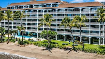 A multi-story hotel with balconies, a pool, and palm trees.