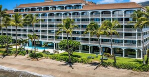 A multi-story hotel with balconies, a pool, and palm trees. - Guest Favorite: Beachfront Studio Turtles, Monk Seals, Surf & Mountain View (Lahaina)