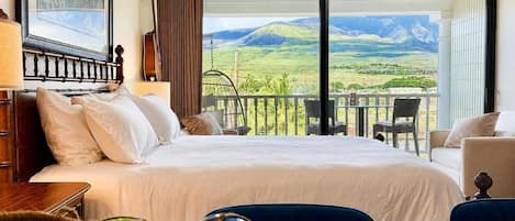 Ein Hotelzimmer mit Bett, Blick auf die Landschaft, einem Balkon mit Stühlen und einer Gitarre an der Wand.