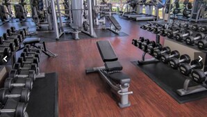 A gym with various exercise equipment including dumbbells, a bench, and cardio machines. - Spacious 3-bedroom condo with AC in beautiful Orlando (Orlando)