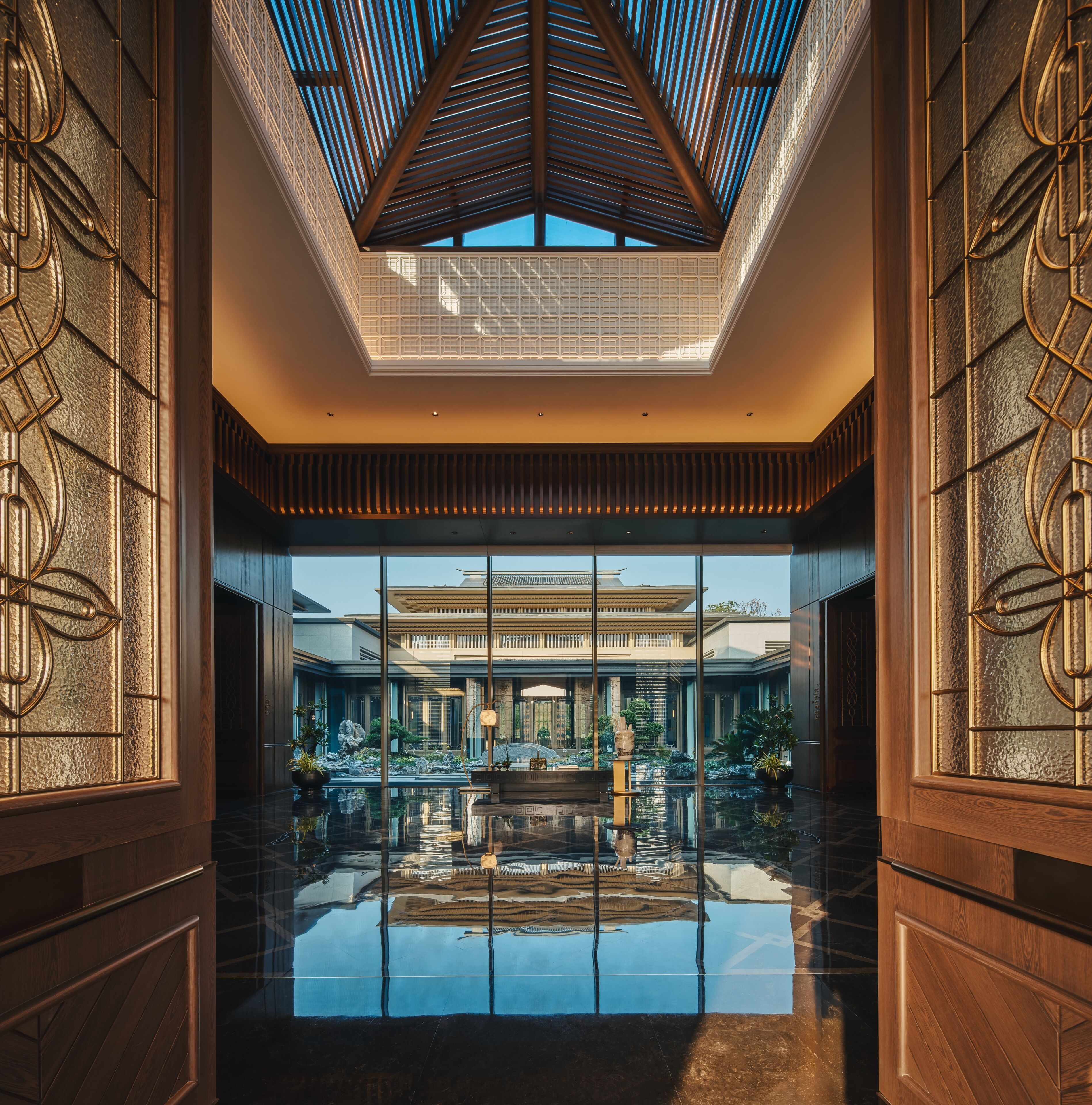 En rymlig entréhall med ett reflekterande golv, ett takfönster och traditionella arkitektoniska detaljer.